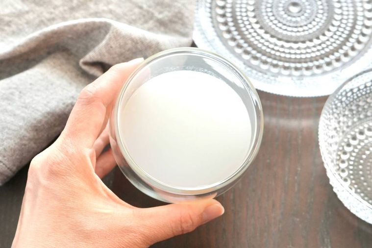 茶色いテーブルにのった乳性炭酸飲料のアンバサファンタが入ったグラスとグレーの布とガラスの器