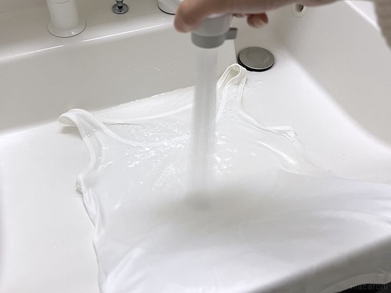 しょうゆがついた服を水で洗っている様子