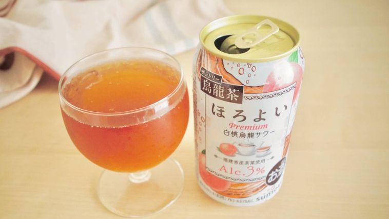 グラスに注がれたほろよい白桃烏龍サワーと缶が置かれている