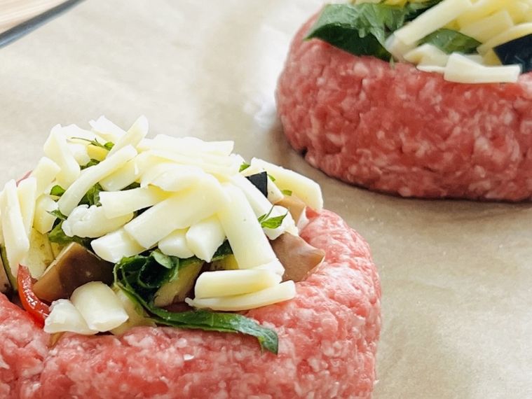 器状に成形した肉ダネに野菜やチーズをのせた様子
