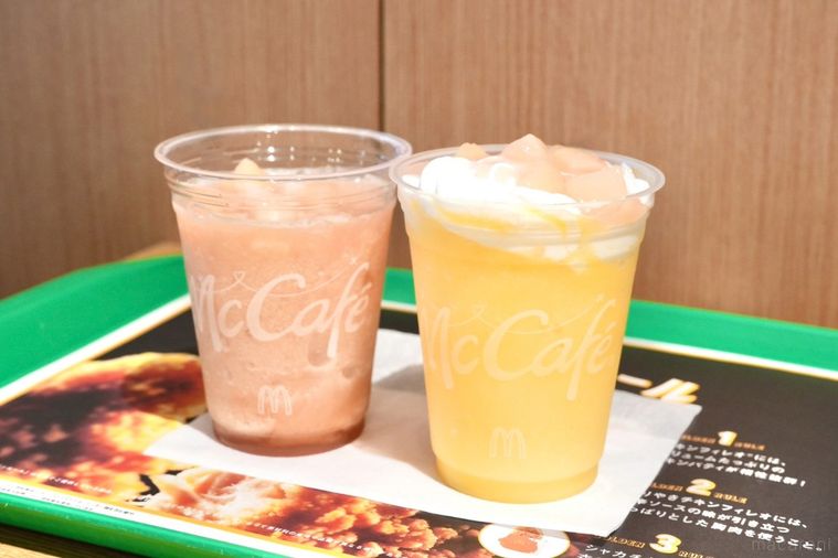 緑色のトレーにのったプラカップ入りの桃味のスムージーとミックスフルーツ味のフラッペ