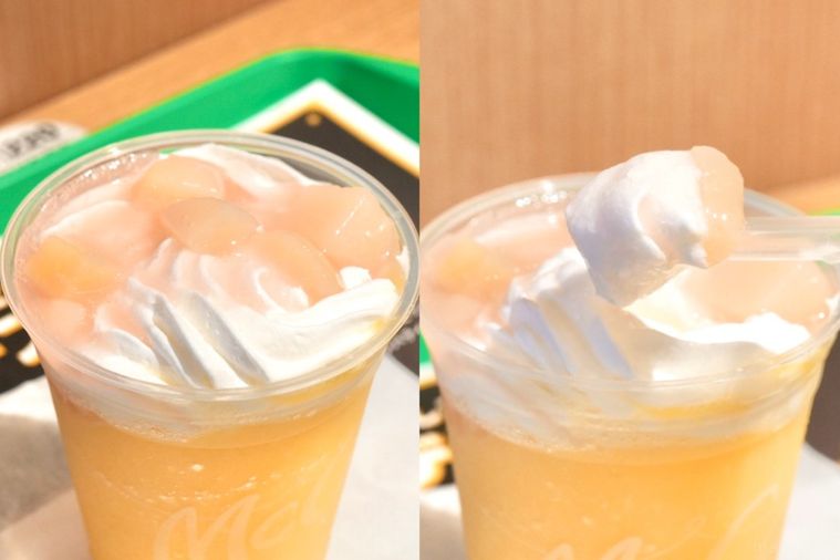 緑色のトレーにのったプラカップ入りのミックスフルーツ味のフラッペのホイップクリームと桃の果肉ソースを持ち上げる様子