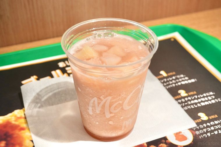 緑色のトレーにのったプラカップ入りの桃味のスムージー