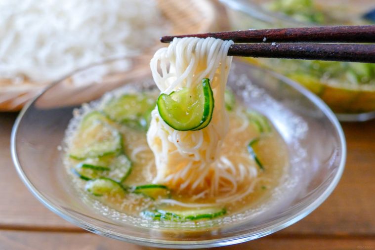 きゅうり入りのそうめんつゆにそうめんをつけて箸で持ち上げる様子
