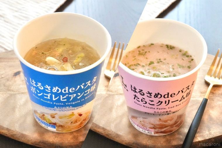 木のカッティングボードにのったカップはるさめパスタの青色とピンク色のパッケージとストライプの布と金と黒のフォーク