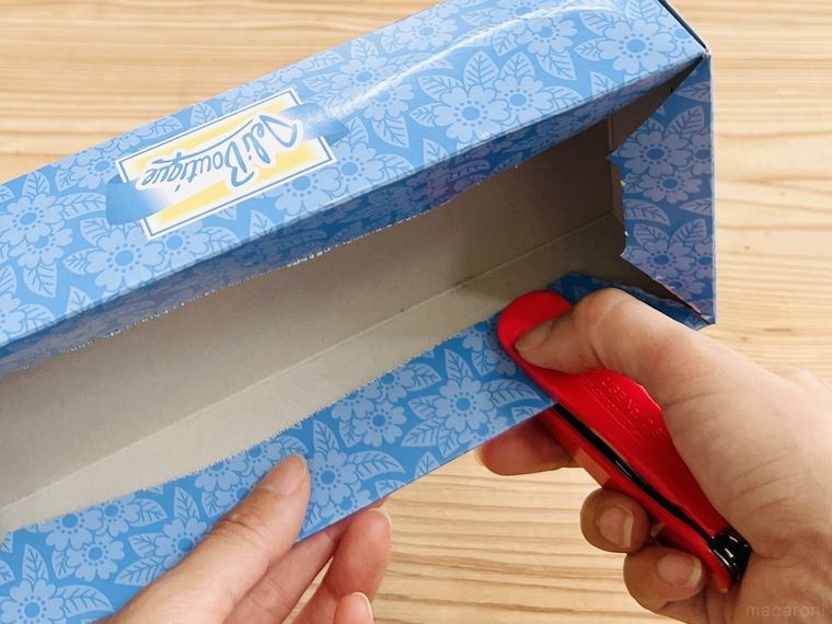 ティッシュの空き箱の上部をホッチキスで留めている様子