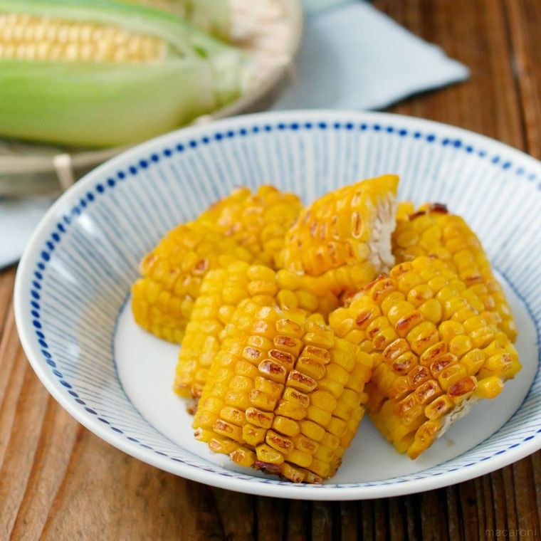 青色の模様が入った白色の皿に盛られた焼きとうもろこし