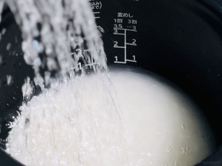 お米が入った炊飯釜に水をそそいでいる様子