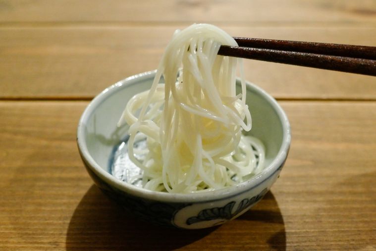 オリーブオイルを絡めて12時間置いたそうめんを箸で持ち上げる様子