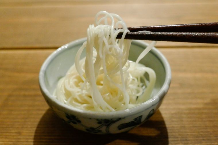 ごま油を絡めて12時間置いたそうめんを箸で持ち上げる様子
