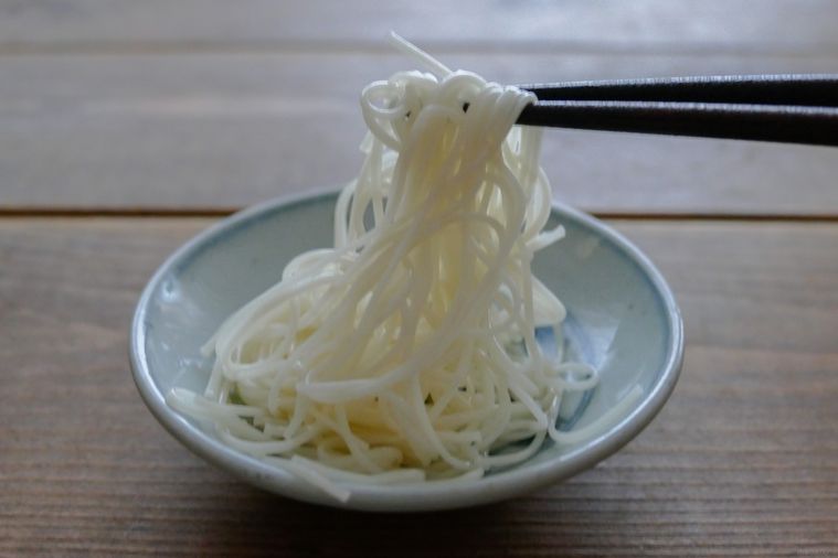 ごま油を絡めたそうめんを箸で持ち上げる様子