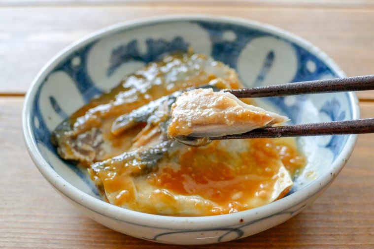 さばの味噌煮を箸でほぐして持ち上げる様子