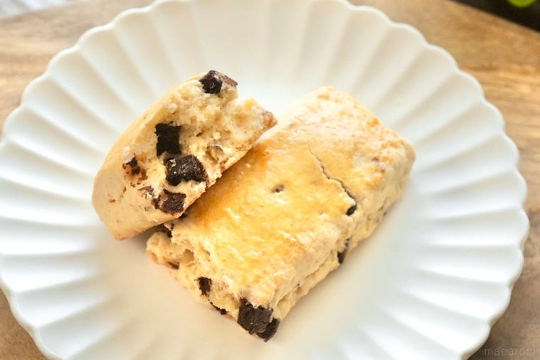 木のカッティングボードと白い皿にのったチョコチップスコーンの断面