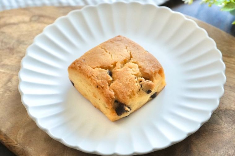 木のカッティングボードと白い皿にのったチョコチップスコーンとストライプの布