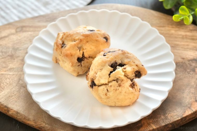 木のカッティングボードと白い皿にのったチョコチップスコーンとストライプの布とグリーン