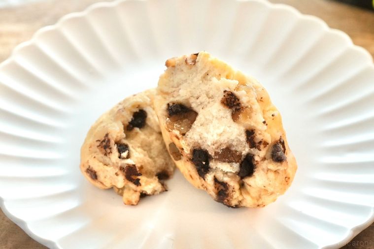 木のカッティングボードと白い皿にのったチョコチャンクスコーンの断面