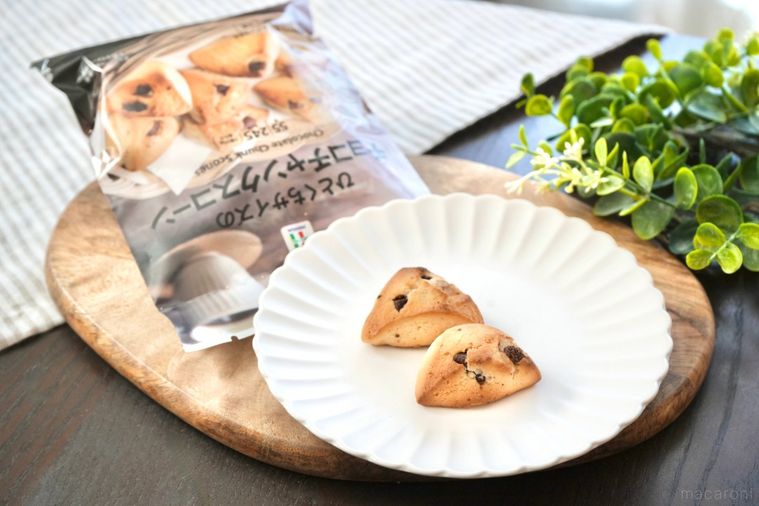 木のカッティングボードと白い皿にのったチョコチャンクスコーンとパッケージの袋とストライプの布とグリーン