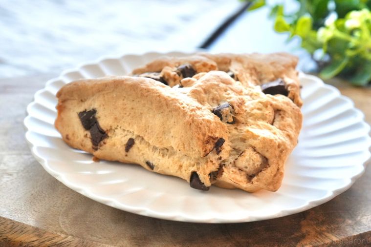 木のカッティングボードと白い皿にのったチョコチップスコーンとストライプの布