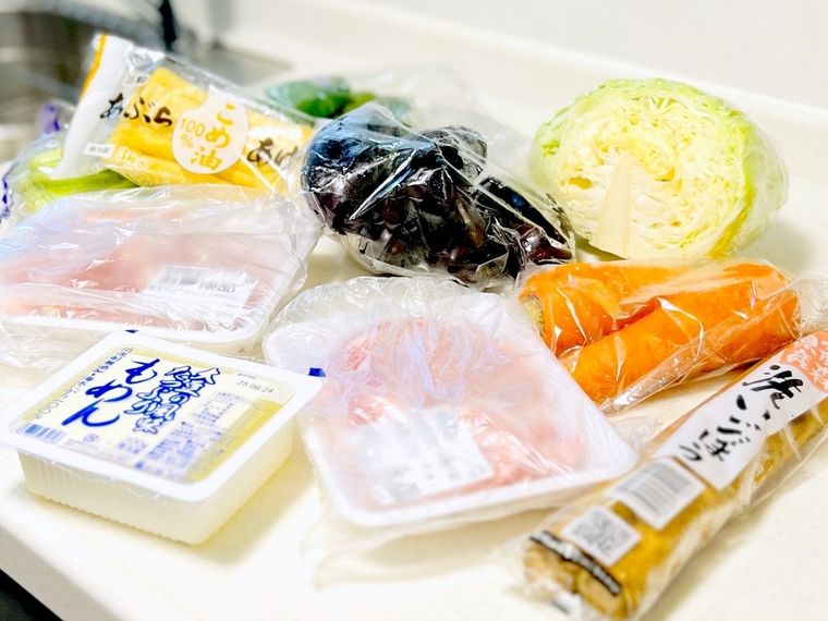 キッチンの調理台に肉や野菜、豆腐などが置かれている様子