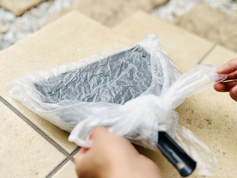 ちりとりにかぶせた袋の口を縛っている様子