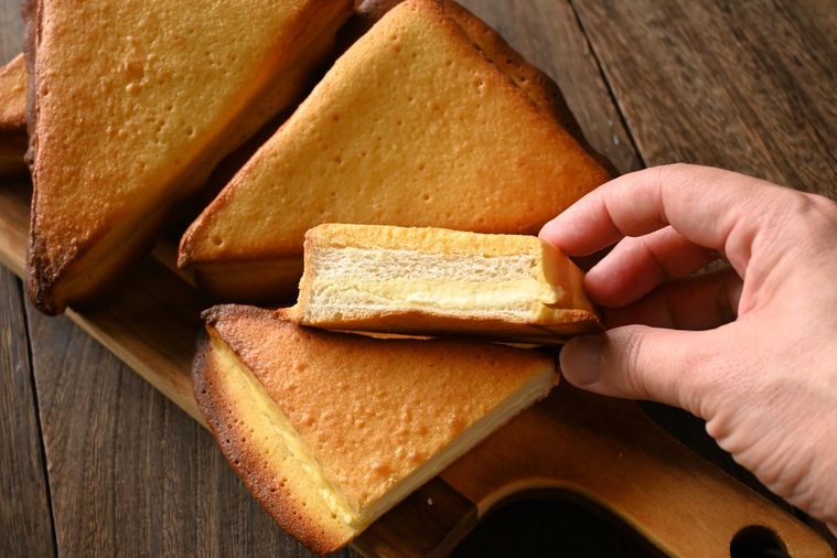 カットした三角チーズパンを手に取る様子
