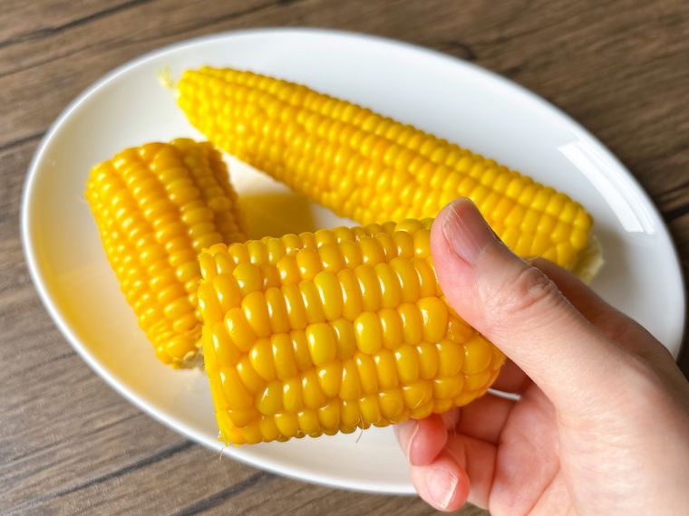 半分にカットしたゆでたとうもろこしを持った様子