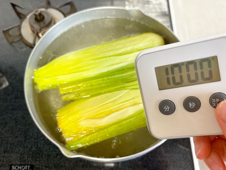 タイマーを持ってとうもろこしをゆでる様子