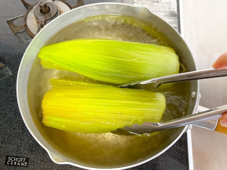 とうもろこしを上下を裏返しながらゆでる様子