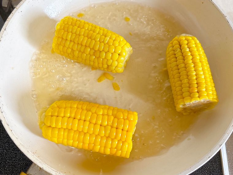 半分にカットしたとうもろこしをフライパンでゆでている様子