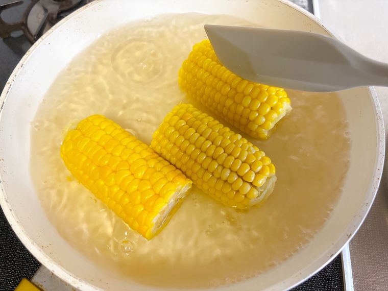 フライパンに入ったとうもろこしをひっくり返す様子