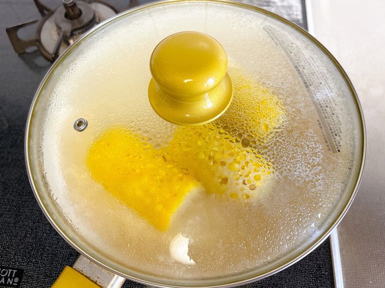 とうもろこしと水、きび砂糖、塩が入ったフライパンに蓋をした様子