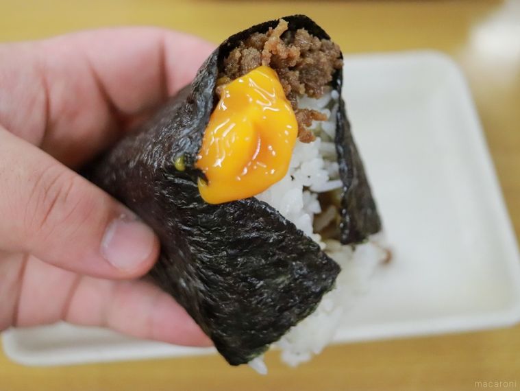 米がおいしいおにぎり戸越屋 戸越銀座本店のおにぎり「卵黄＋肉そぼろ」を手に持っている様子