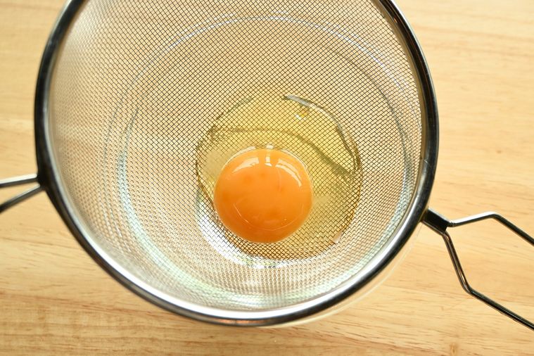 ザルで卵の白身のサラサラした部分をこす様子