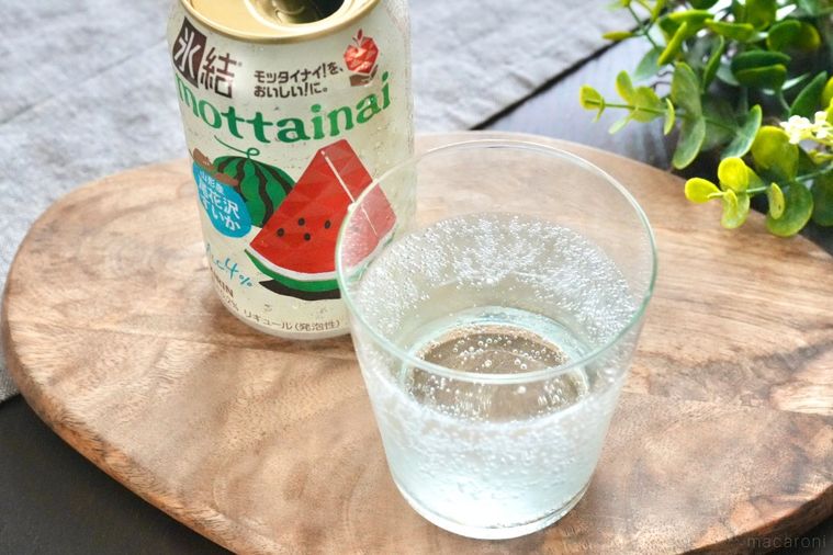 木のカッティングボードにのったグラスに注がれた尾花沢すいかの缶チューハイ