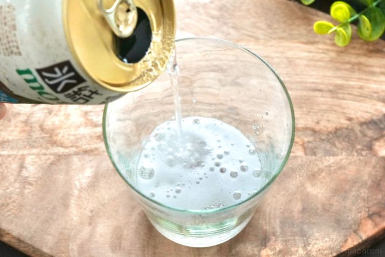 木のカッティングボードにのったグラスに尾花沢すいかの缶チューハイを注ぐ様子