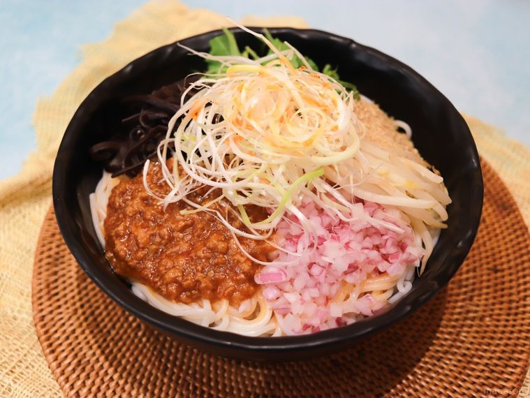 藁でできたコースター風のランチョンマットの上にタムジャイサムゴーの汁なし麻辣担々米線が置いてある