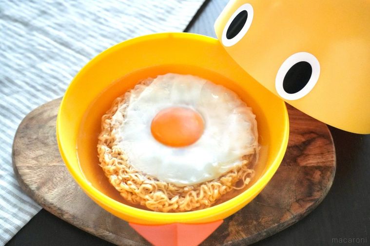 黄色いひよこ型どんぶりに入ったたまごのせチキンラーメンとストライプの布