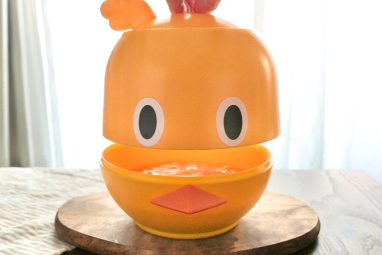 木のカッティングボードにのったひよこ型のラーメンどんぶりガジェットにフタを被せる様子