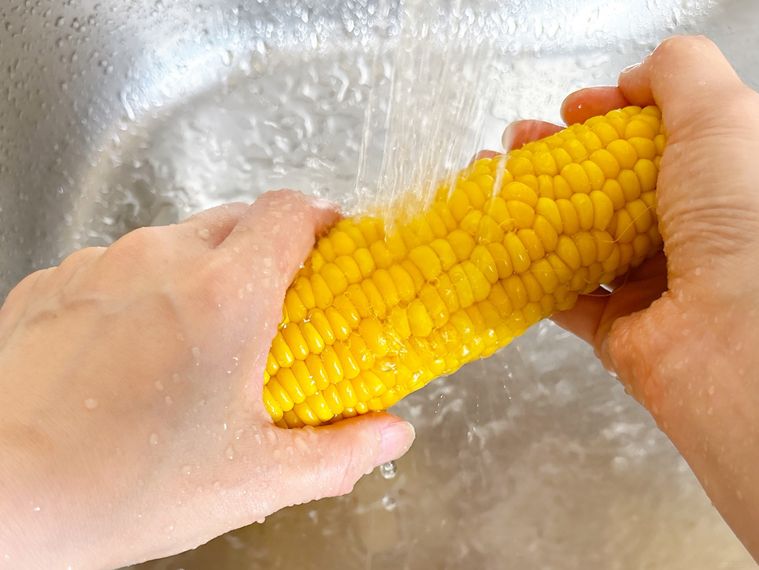 とうもろこしを流水でやさしく洗い流す様子