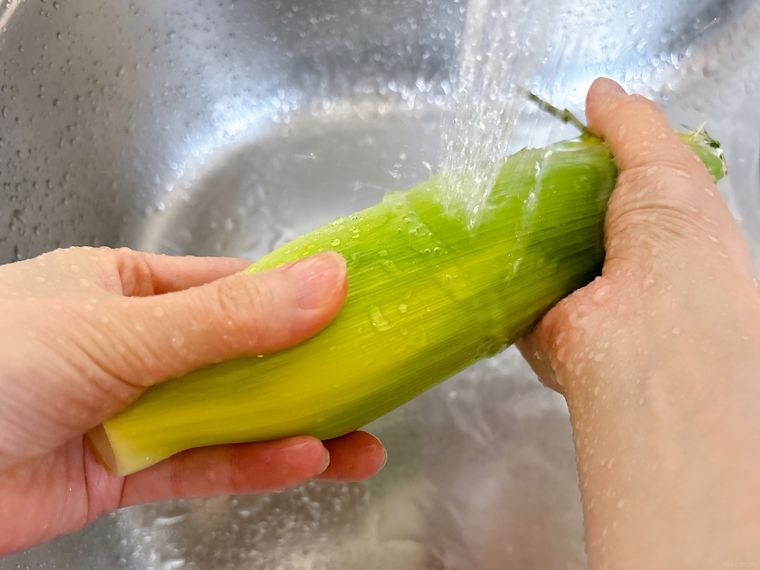 とうもろこしの外側の皮を洗う様子