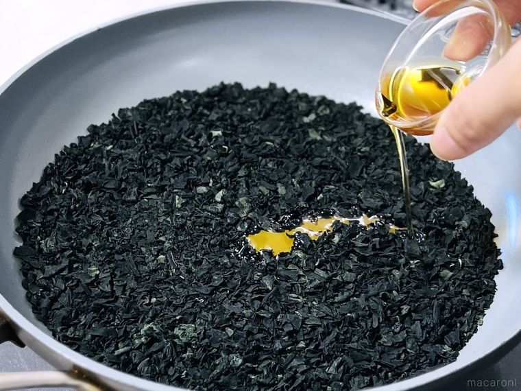 乾煎りしたカットわかめにごま油を加えている様子