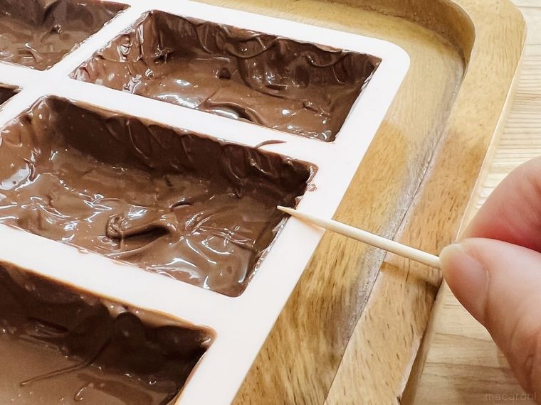型からはみ出したチョコレートをつまようじで取っている様子