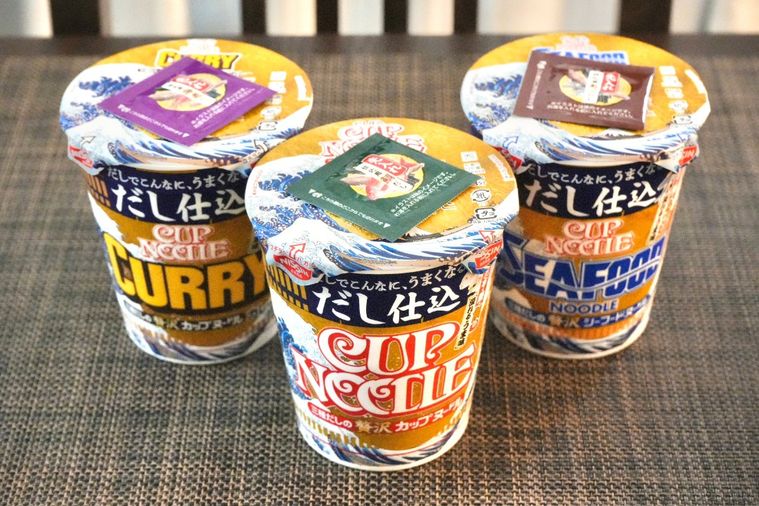 茶色いテーブルとクロスに並べられただし仕込みのカップヌードル3種