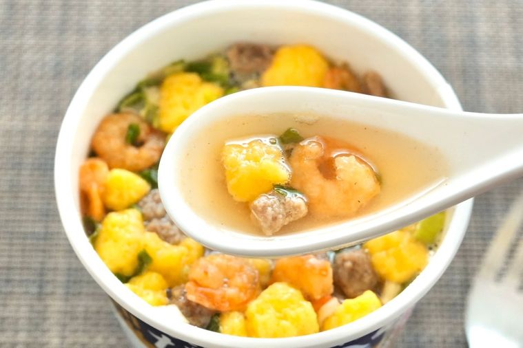 だし仕込カップヌードルのスープを白いレンゲですくう様子