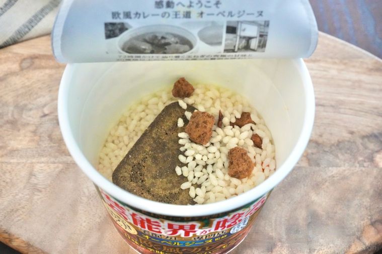 木のカッティングボードにのったカレーカップメシのフタを開けた中身