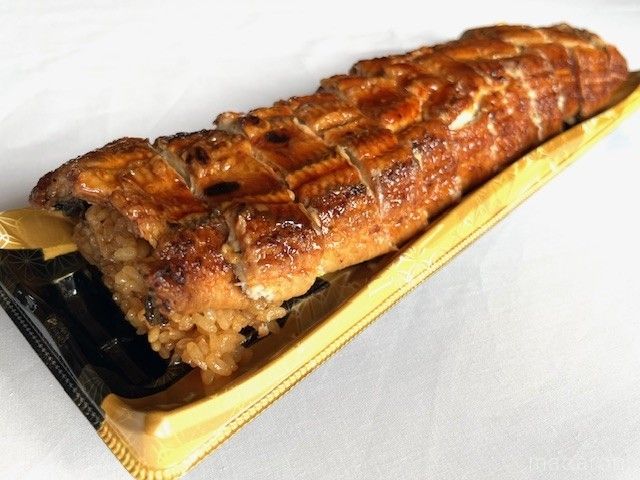 大きな鰻の蒲焼きがのった寿司がテーブルに置いてある