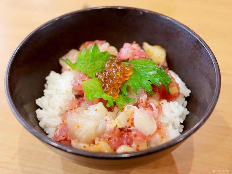 黒い丼に盛り付けられたくら寿司のランチメニュー「旬の海鮮丼」が木製のテーブルに置かれている