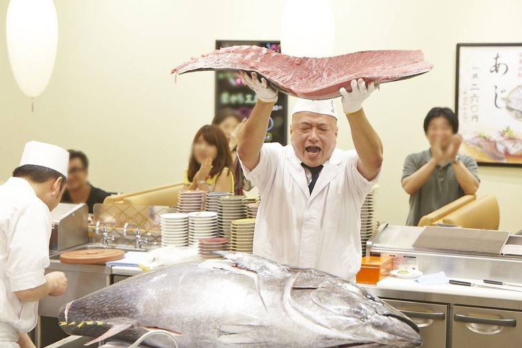 解体した生マグロを持ち上げている寿司職人