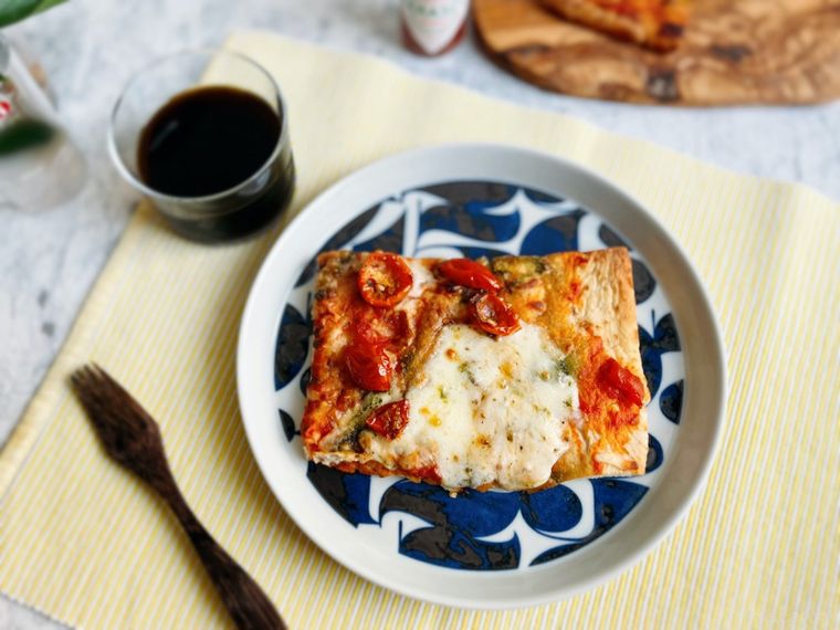 焼いたコストコのピンサマルゲリータをブルーの模様が入ったプレートに盛り付け、フォークとアイスコーヒーを添えたところ