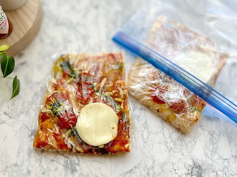 カットしたコストコのピンサマルゲリータを1枚ずつラップで包み保存袋に入れているところ